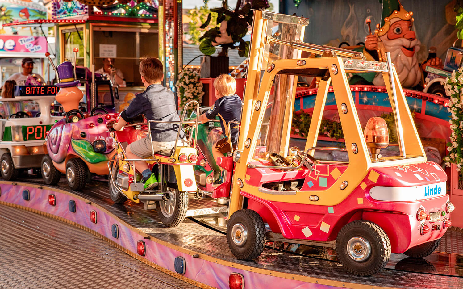 Die Kinderschleife fährt mit verschiedenen Fahrzeugen im Kreis, darunter Motorräder und Gabelstapler