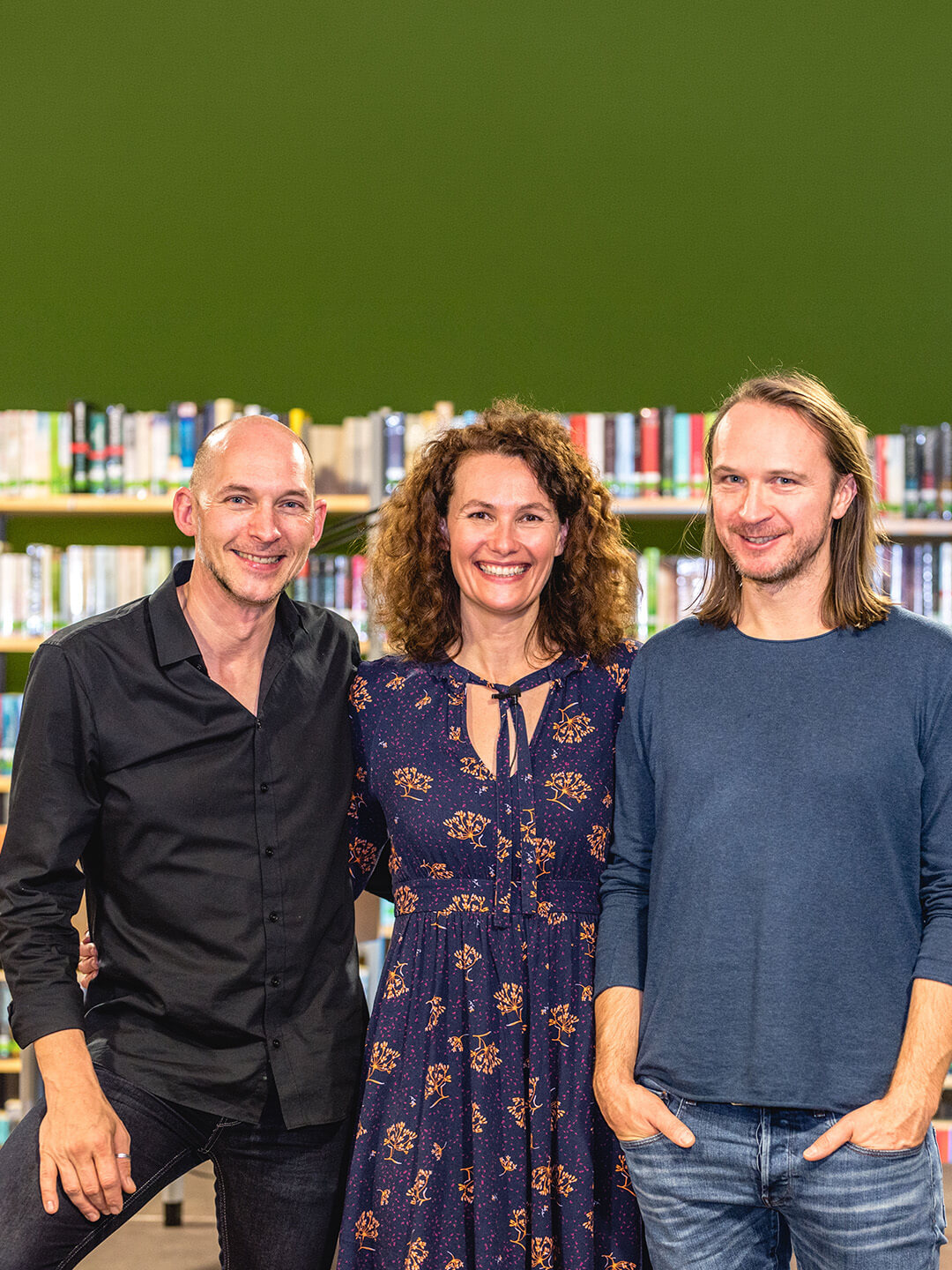 Drei Personen stehen vor einem Bücherregal